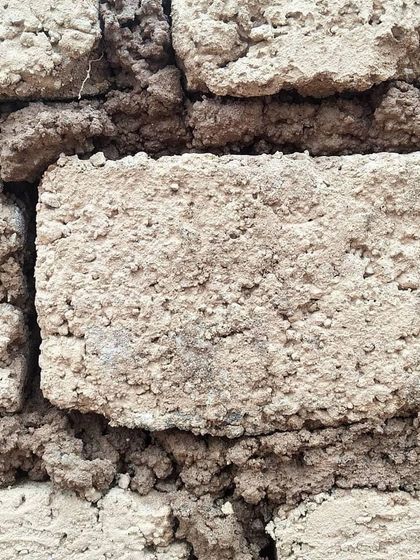 A close-up view of an adobe brick wall. Made from sun-dried earth, these bricks have a beautiful, rustic texture and provide excellent thermal mass, helping to keep the interior of the home cool naturally.