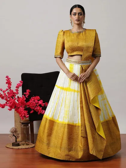 A unique tie-dye lehenga in mustard yellow and ivory, paired with a matching blouse and a draped dupatta for a modern, bohemian look.