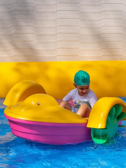 A young boy in a turban enjoys a ride in one of our colorful paddle boats. I make sure our activities are fun and accessible for every child.