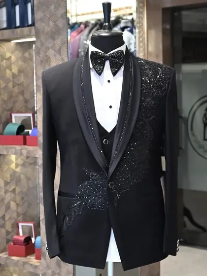 A black three-piece tuxedo with intricate, sparkling peacock feather embroidery. This is a perfect example of how I use detailed handwork to create a truly one-of-a-kind garment.