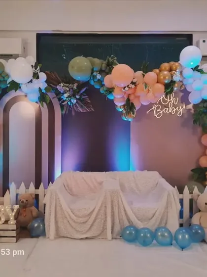 A lovely boho-themed setup with a white picket fence. The earthy tones of the balloon arch, combined with an 'Oh Baby' sign and teddy bears, create a warm and rustic feel.