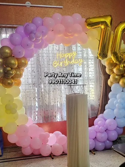A colorful circular balloon arch for a 70th birthday celebration at home. The pastel balloons and large foil numbers create a cheerful atmosphere.