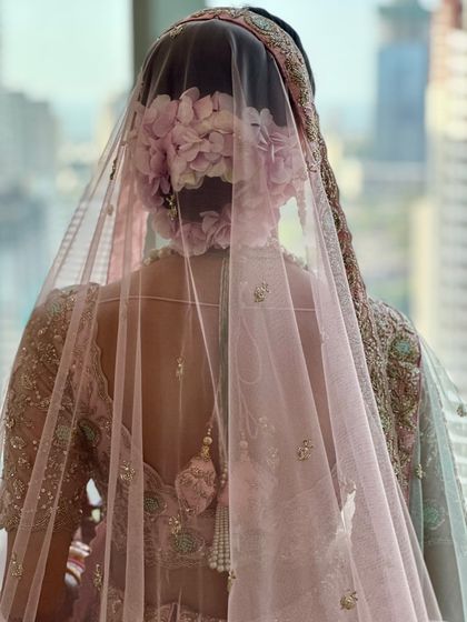 A view of the stunning floral hair bun, which adds a touch of romance to the overall look. The sheer pink veil complements the soft and dreamy makeup perfectly.