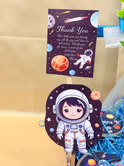 To the moon and back! A close-up of the custom thank you card and astronaut cutout for Ayaan's space-themed birthday hamper.