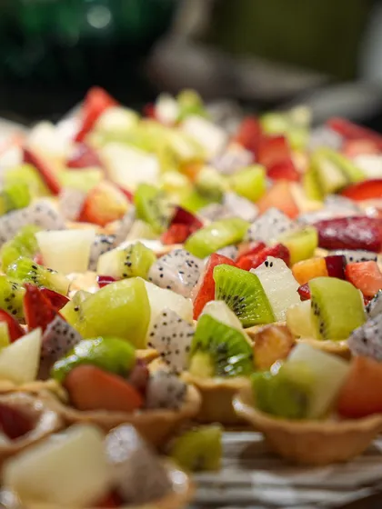 A close-up of our fresh fruit tarts, loaded with kiwi, dragon fruit, and strawberries. A vibrant and refreshing option on our dessert buffet.
