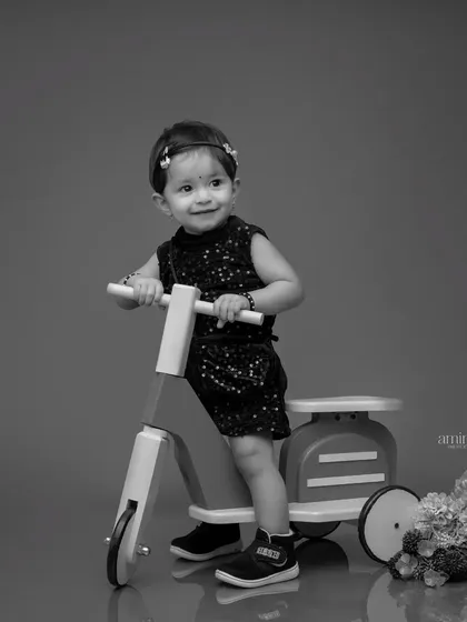 A timeless black and white photo of a little girl on a toy scooter. This classic edit focuses on her expression and the clean lines of the composition.