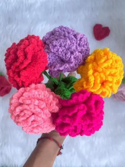 A handful of colorful crochet carnations. Carnations symbolize love and fascination, and these fluffy, bright flowers will brighten anyone's day.