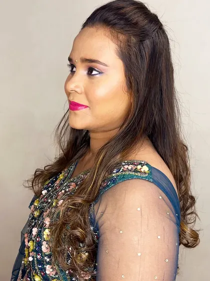 A side view showing her half-up, half-down hairstyle with soft waves, a versatile choice for a sangeet.