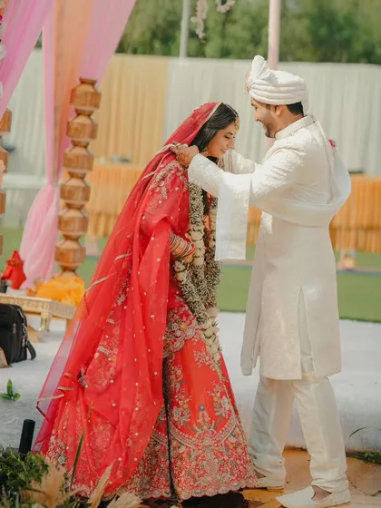 A tender moment during the ceremony, as the groom gently places the dupatta on the bride's head.