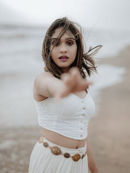 A captivating portrait with the model reaching towards the camera. The wind in her hair and the soft focus on the hand create a sense of intimacy and movement.