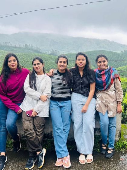 A group of friends posing against the backdrop of Munnar's rolling tea gardens. The misty weather adds to the charm of this beautiful hill station.