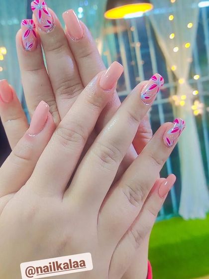 A pretty and feminine design with a solid peach base and accent nails featuring delicate pink floral patterns.