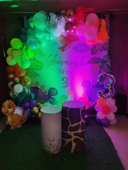 The same dinosaur theme, but this time under colorful party lights. This shows how the decor can be transformed with different lighting to create a fun, disco-like atmosphere for the kids.