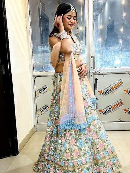 A side view of the pastel floral rental lehenga, highlighting the delicate embroidery and the pretty ruffled border on the dupatta.