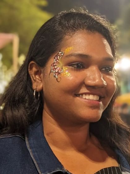 A smiling client with a beautiful butterfly design, accented with warm gold glitter that glows in the evening light.