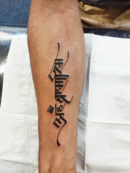 The powerful Sanskrit mantra 'Aham Brahmasmi' (I am the absolute) in a bold, calligraphic style. This forearm tattoo is a strong statement of self-realization.
