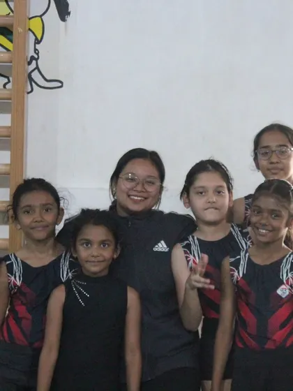 A coach with her group of young gymnasts. We foster a supportive and friendly environment where students feel comfortable and motivated.