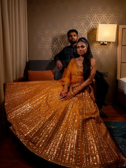 A regal portrait of the couple at their sangeet. The bride's shimmering yellow lehenga is the star of the show.