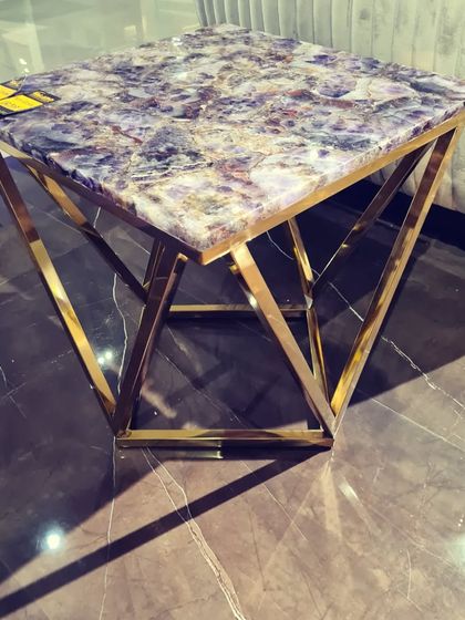 For a truly unique statement, we offer tables with semi-precious stone tops. This corner table features a stunning amethyst top set on a gold-finished geometric base, turning a functional piece into a work of art.
