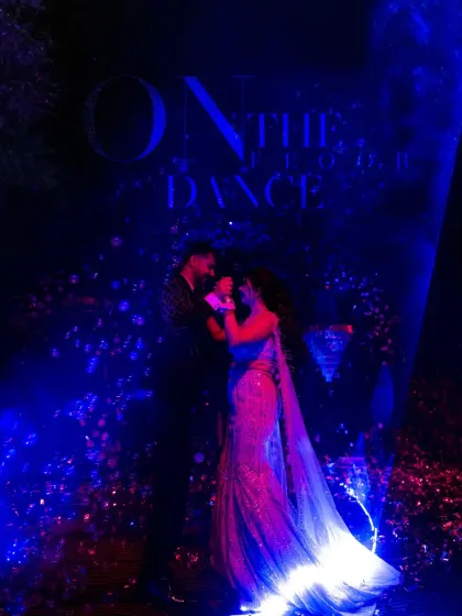 A magical Sangeet night portrait under a canopy of blue and purple lights. The atmosphere is dreamy and romantic, perfect for a couple's dance.