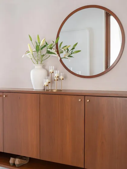 The foyer in 'Living life in colours' is a subtle prelude to the vibrant home inside. It features a teak shoe cabinet set against a soft peach textured wall.