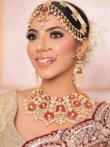 A happy bride smiling, wearing the full red and white meenakari rental set. This is the kind of joy I love to see.