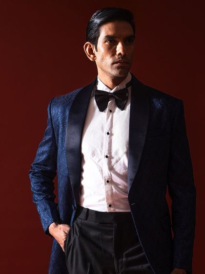 A portrait of classic elegance. This textured navy blue tuxedo jacket with a satin shawl lapel is a cornerstone of formal menswear, offering a timeless look for any black-tie affair or special occasion.