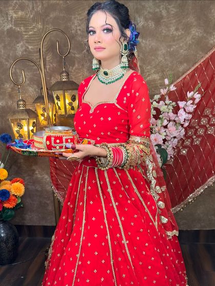 A full-length view of the red lehenga, showing its beautiful flare and gold detailing. It's a perfect outfit for looking your best during the evening puja.