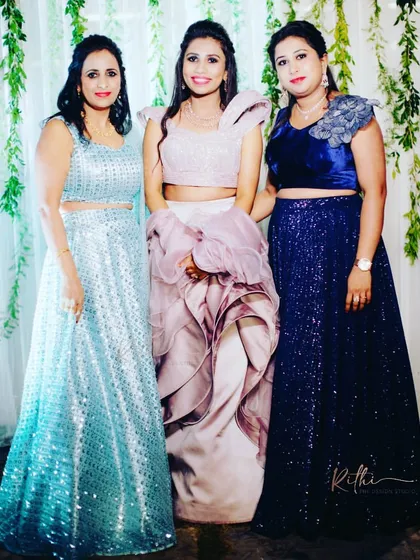 A group of beautiful ladies ready for a sangeet, all wearing custom-designed outfits in shades of blue, mauve, and navy.