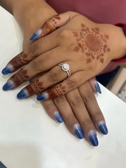 Another view of the blue and silver glitter ombre nails. The gradient effect is created by carefully blending the polishes to ensure a smooth transition from silver to deep blue.