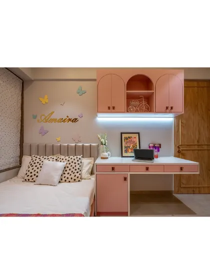 This bedroom features a built-in study desk with overhead storage, all in a charming pastel pink. The design is perfect for a young student, providing a dedicated space for creativity and learning.