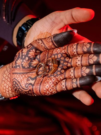 The engagement rings resting in the bride's palm, surrounded by the deep, rich color of her fully developed henna stain.