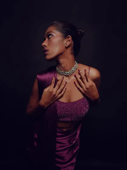 A full body shot showing the dramatic lighting and the rich color of the outfit. The makeup is designed to stand out even in low light conditions.