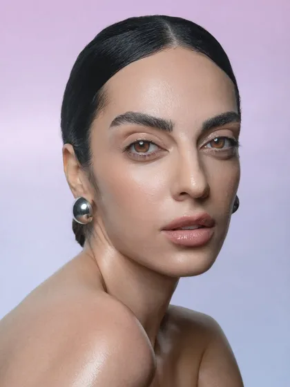 This portrait focuses on the strong brows and radiant skin. The slicked-back hair keeps the attention on the face, making it a powerful shot for a beauty or skincare advertisement.