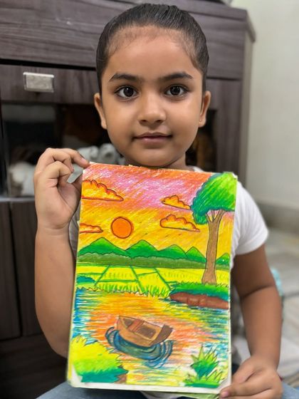 A young artist holds her beautiful sunset scenery, a testament to her imagination. We learn techniques like blending oil pastels to create stunning effects like this colourful sky.