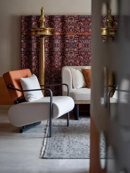 A view of the living room from the side, showing the modern armchair and the traditional brass diya. The space is a beautiful dialogue between different styles and eras.