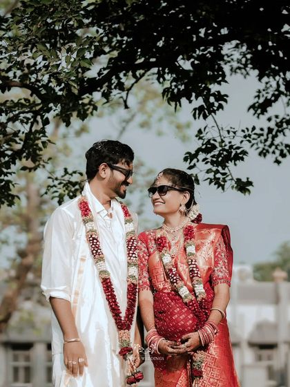 The couple smiling at each other, wearing sunglasses for a fun and modern twist on their traditional wedding portraits.