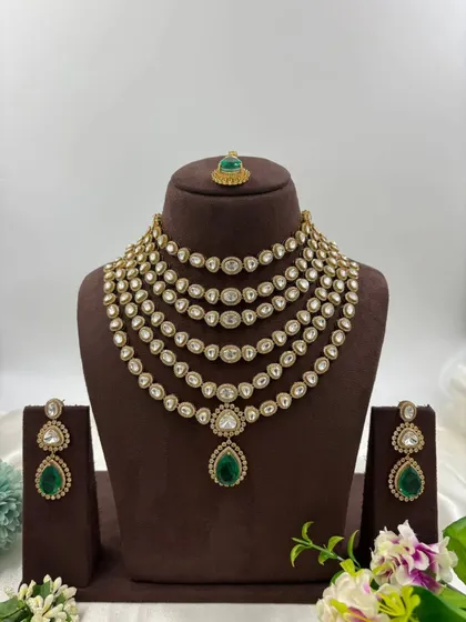 For a truly regal statement, nothing compares to a multi-layered polki and kundan necklace. This 'Satlada' style haar, with its rows of uncut stones and a striking emerald green pendant, is available to rent for a majestic bridal or reception look.