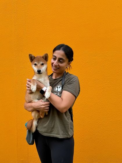 A happy hug with a Shiba Inu pup against our bright orange wall.