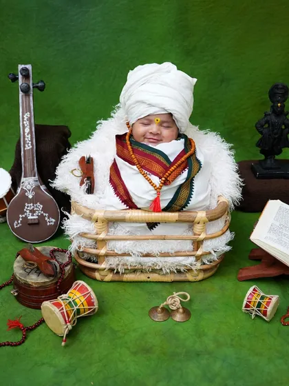 Our tiny warkari dreams of music and devotion, surrounded by a miniature tanpura, dholki, and cymbals against a vibrant green backdrop.