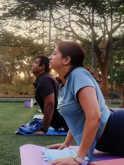 Students practicing Urdhva Mukha Svanasana (Upward-Facing Dog) during a morning park session. This heart-opening pose helps improve posture and energize the body.