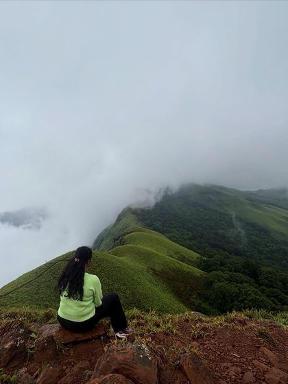Sitting on the edge and watching the clouds drift over the green hills of Netravathi. It's a moment of pure peace and connection with nature.