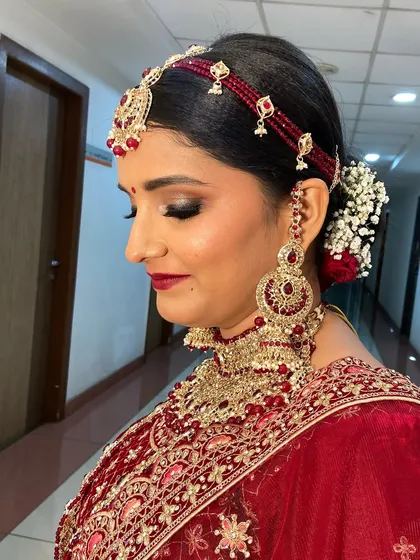 A close-up of the bridal makeup, focusing on the smoky eye and deep red lip color that brings a touch of Bollywood glam to her traditional wedding look.