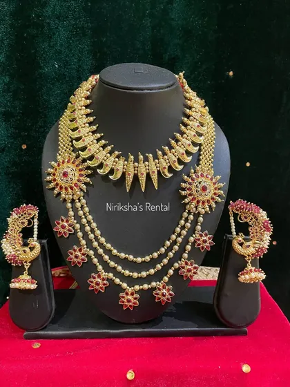 This layered necklace set with floral motifs and pearl drops offers a unique and elegant look for a bride or wedding guest.