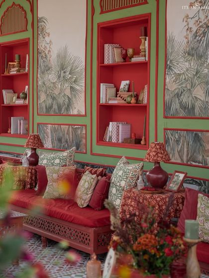 The luxurious lounge seating with custom block-printed cushions and built-in red shelves filled with curated books and artifacts, creating a personal and lived-in feel.