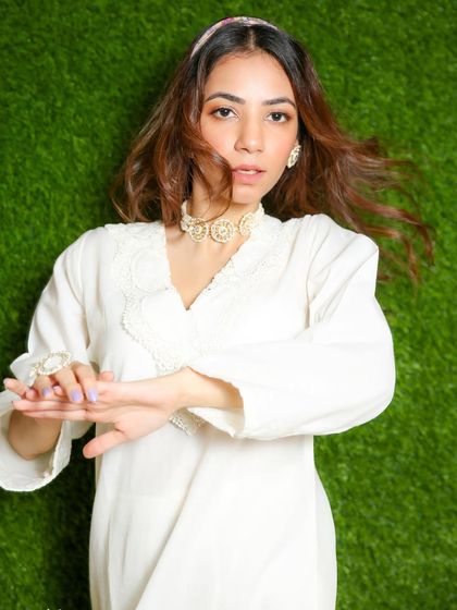 A dynamic shot with movement, capturing the flow of the model's hair and the light fabric of her white kurta.