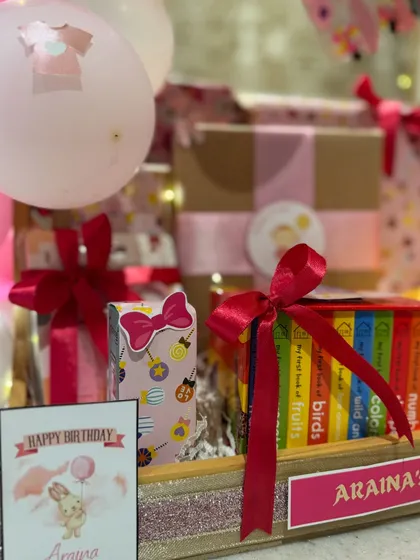 A close-up of the details, including a personalized birthday card and a set of 'My First Library' board books, perfect for a one-year-old.