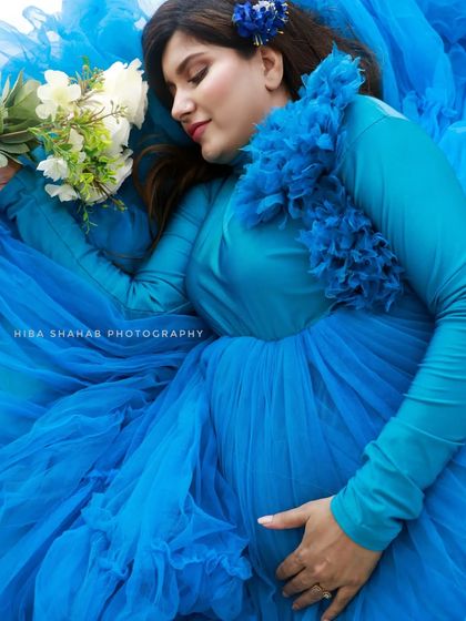 A creative shot of a client lying in a sea of blue tulle from her gown. This shows the artistic possibilities that come with renting a voluminous, textured dress.