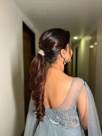 The back view of the ideal parted ponytail, secured with a sparkling cuff. The ends are curled for a soft, romantic finish.