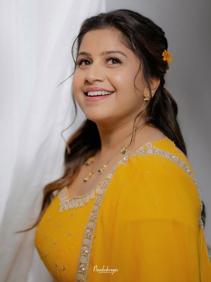 A candid portrait of the bride, looking up with a radiant smile. This shot captures her natural glow and excitement on her Haldi day.